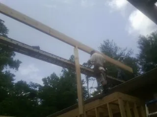 Carpenter setting a ridge beam over a new addition frame — Ice Dam Removal by Roofing Brothers in Flushing