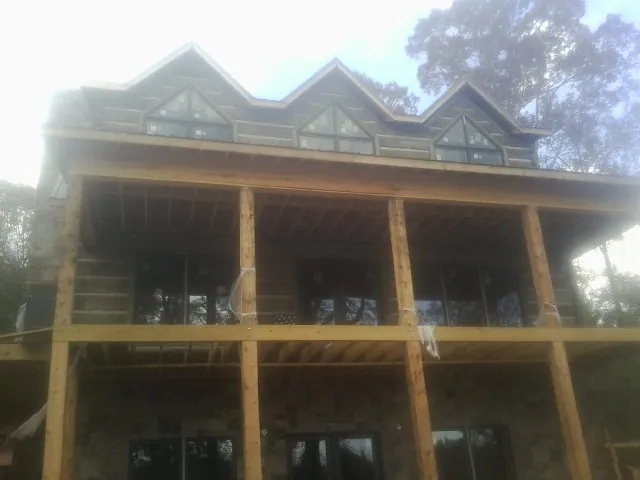 Dormers and porch framing on a large log home under construction — Roof Coating work by our crew in Flushing