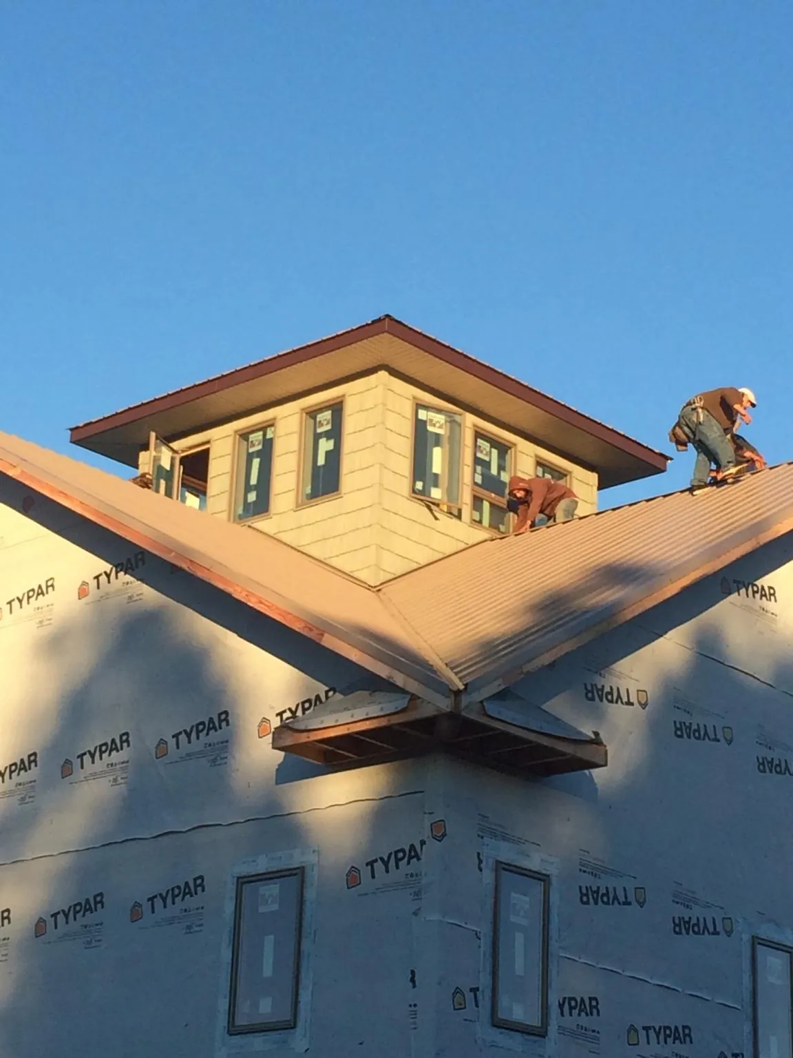 Roofers working around a rooftop cupola on a new metal roof at sunset — Roof Waterproofing in Flushing by Roofing Brothers